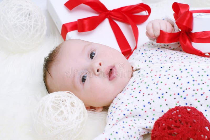 Un'età del bambino di 3 mesi che si trovano fra i regali fotografie stock libere da diritti Un'età del bambino di 3 mesi che si trovano fra i regali fotografie stock libere da diritti