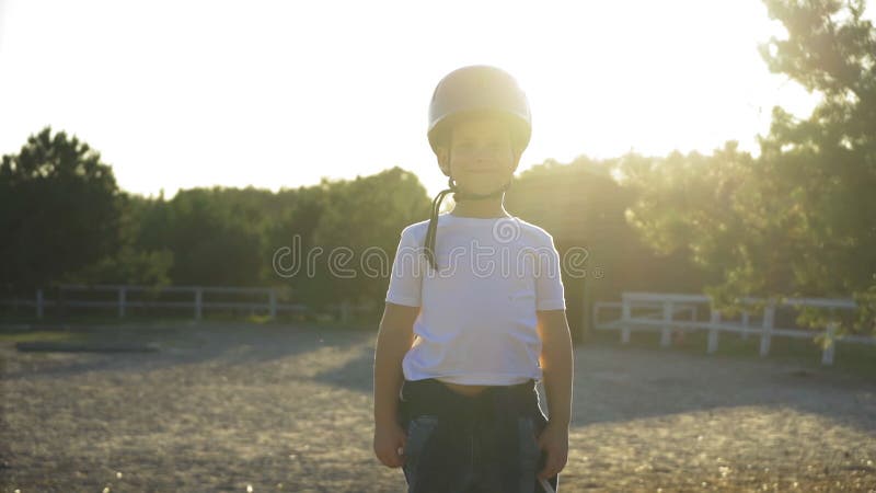 Un fantino con un casco in attesa del suo istruttore all'aperto. il bambino impara con un istruttore a cavallo