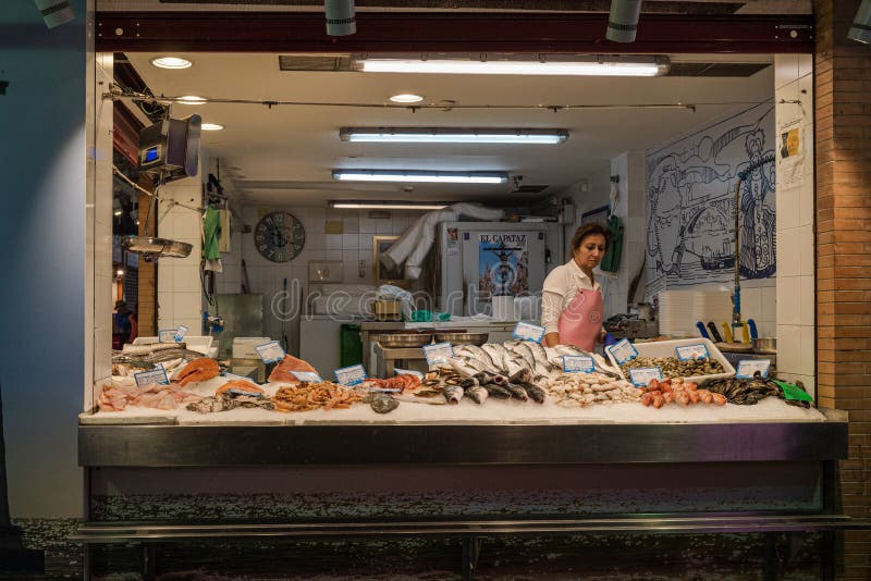 Triana, Seville, Spain -- May 27, 2022. A woman wokring at a fish stand in the Triana market in Seville, Spain. Triana, Seville, Spain -- May 27, 2022. A woman wokring at a fish stand in the Triana market in Seville, Spain