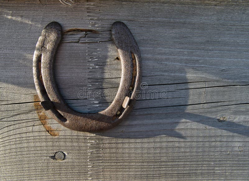 Un ferro di cavallo su un bordo di legno come incanto fortunato fotografia stock libera da diritti Un ferro di cavallo su un bordo di legno come incanto fortunato fotografia stock libera da diritti