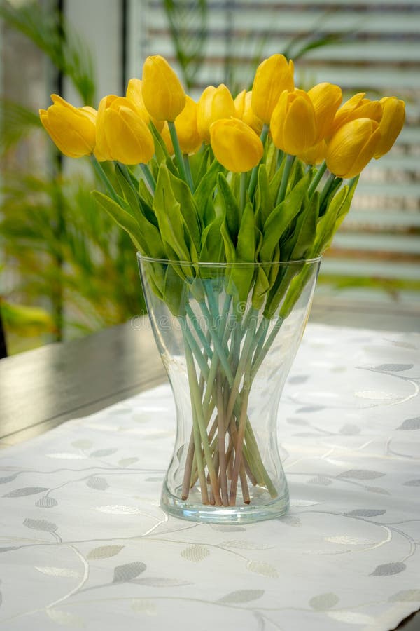 Un florero con los tulipanes amarillos está en la tabla imagen de archivo libre de regalías Un florero con los tulipanes amarillos está en la tabla imagen de archivo libre de regalías