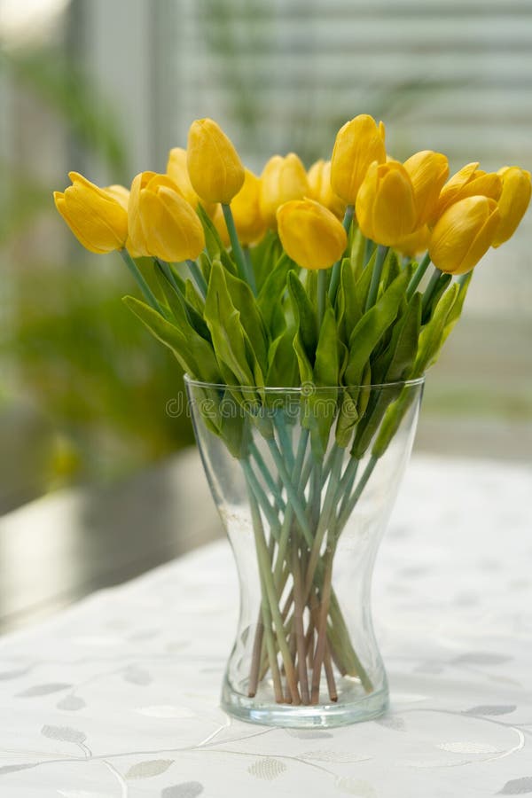 Un florero con los tulipanes amarillos está en la tabla foto de archivo Un florero con los tulipanes amarillos está en la tabla foto de archivo