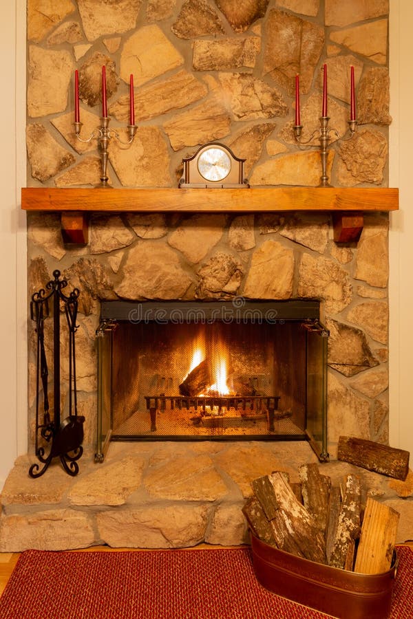 Un foc cald într-un frumos șemineu de piatră cu ceas și candelabre pe mantaua. royalty free stock image