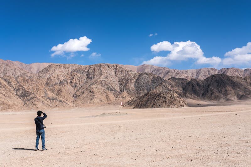 Un fotógrafo del hombre que toma una foto del paisaje de montañas y del cielo azul en Ladakh fotos de archivo libres de regalías Un fotógrafo del hombre que toma una foto del paisaje de montañas y del cielo azul en Ladakh fotos de archivo libres de regalías