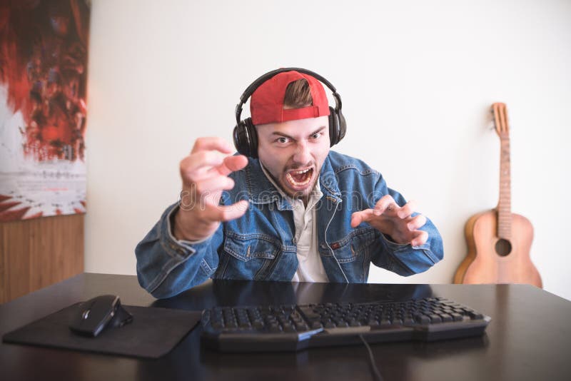 Un gamer emozionale gioca su un home computer e si arrabbia con la sconfitta Concetto del video gioco immagini stock libere da diritti Un gamer emozionale gioca su un home computer e si arrabbia con la sconfitta Concetto del video gioco immagini stock libere da diritti