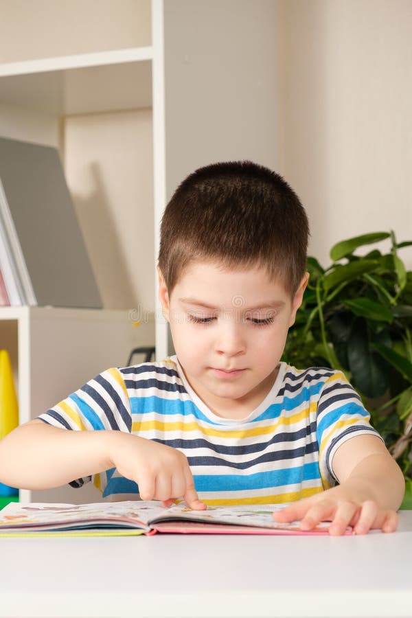 Un Garçon Heureux De 4 Ans Regarde Un Livre Avec Des Photos