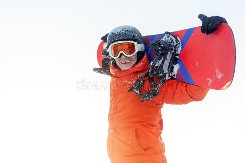 Un gars joyeux en vêtements de ski tient snowboard et sourit à l'homme de la station en casque orange et lunettes se réjouissent photo stock