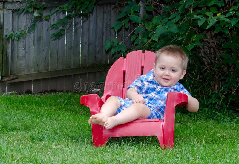 Un garçon an dans la chaise rouge photo stock Un garçon an dans la chaise rouge photo stock