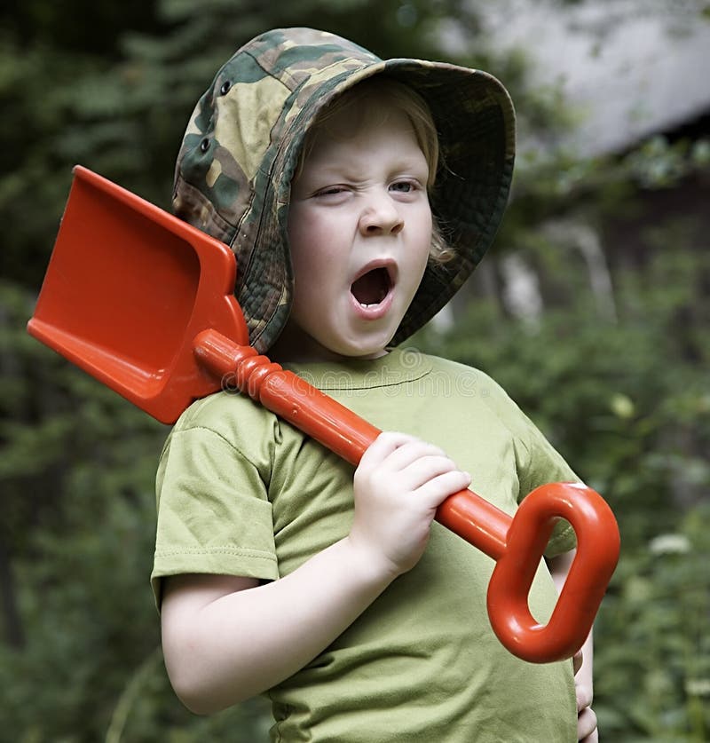 A boy in the garden with red spade. A boy in the garden with red spade