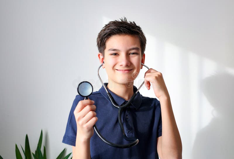 Un garçon jouant au médecin avec stéthoscope isolé sur fond léger. photo stock