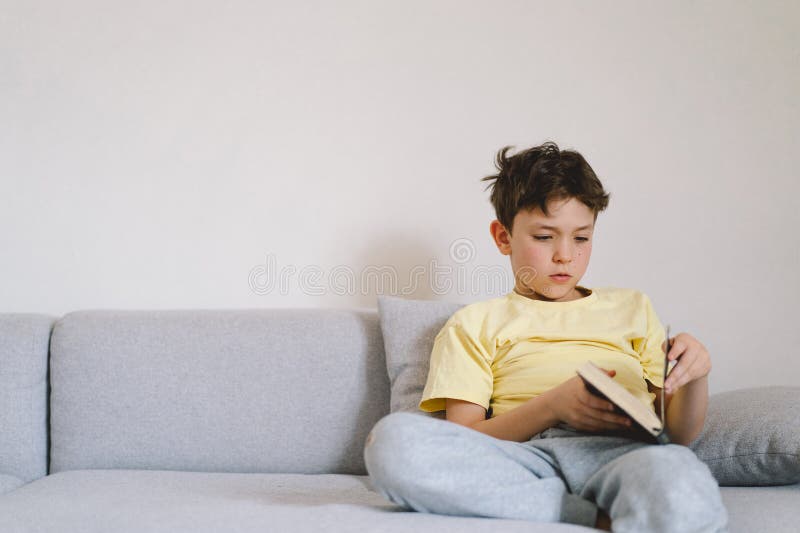 Un garçon lisant un livre intéressant photographie stock