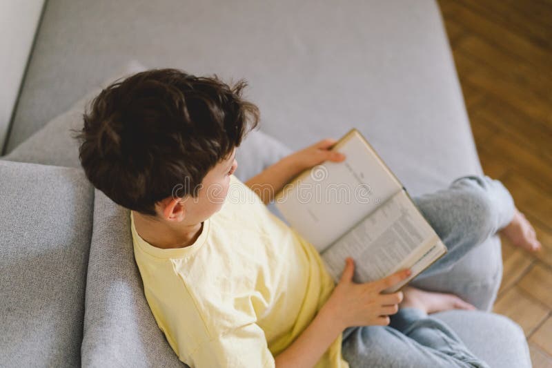 Un garçon lisant un livre intéressant image stock
