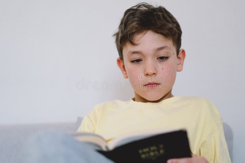 Un garçon lit la sainte bible. photo stock