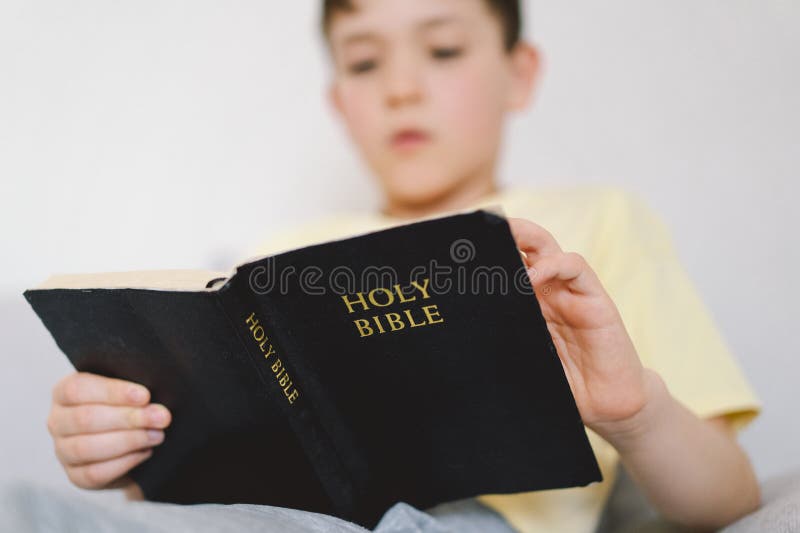 Un garçon lit la sainte bible. images libres de droits