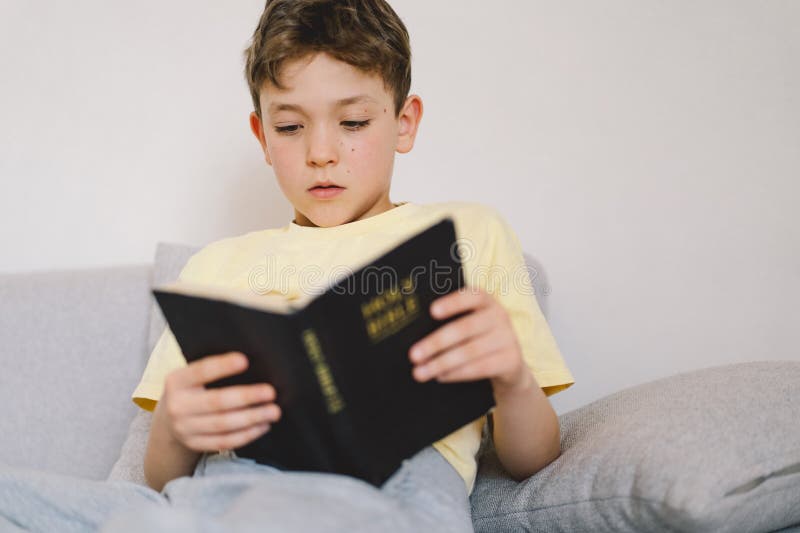 Un garçon lit la sainte bible. photos stock