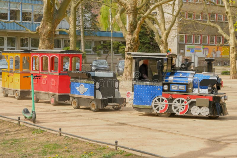 Cute boy rides the railroad on a children's colored locomotive. Children's recreation in an amusement park. children's steam locomotive for riding. Cute boy rides the railroad on a children's colored locomotive. Children's recreation in an amusement park. children's steam locomotive for riding