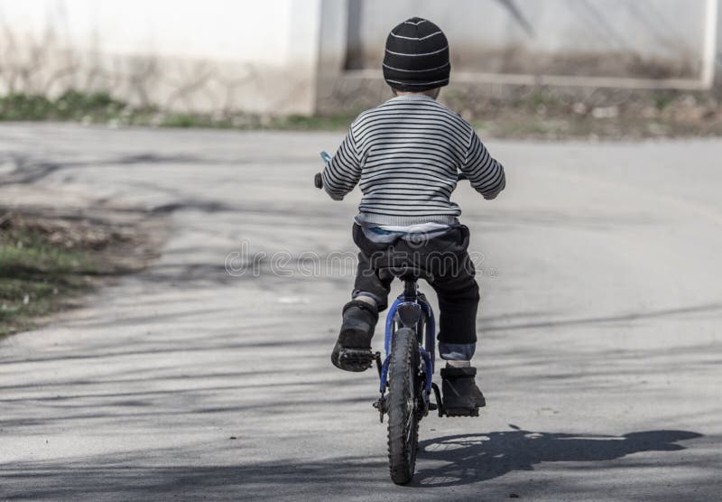Un garçon monte un vélo sur la route photographie stock libre de droits Un garçon monte un vélo sur la route photographie stock libre de droits