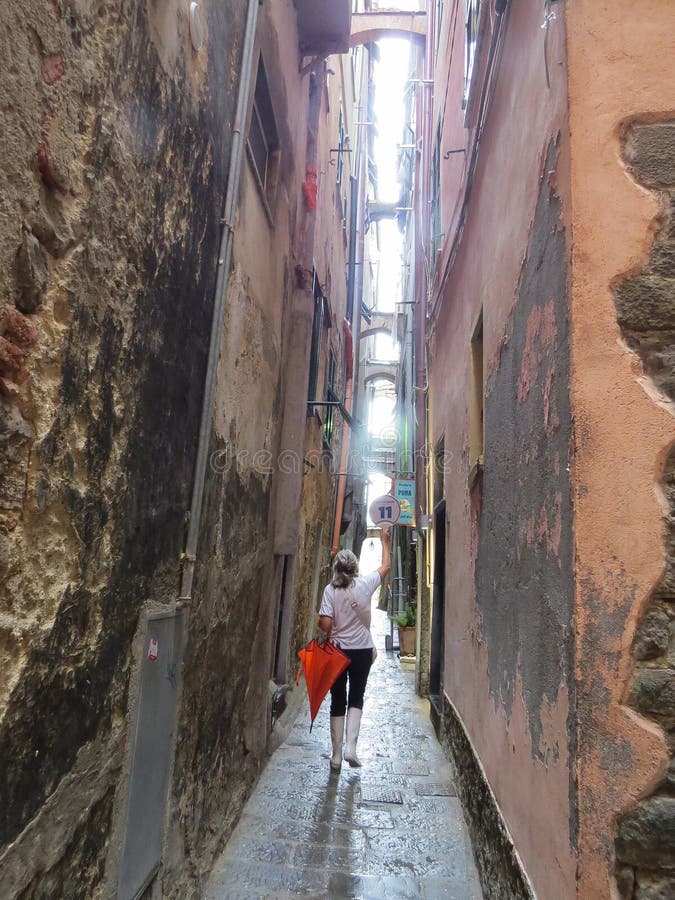 Un giorno di estate piovoso, la guida conduce un giro della via stretta della città costiera di Manarola immagini stock libere da diritti Un giorno di estate piovoso, la guida conduce un giro della via stretta della città costiera di Manarola immagini stock libere da diritti