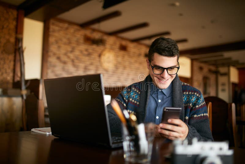 Un giovane che scrive un testo a macchina sullo smartphone moderno mobile Pantaloni a vita bassa che tengono un telefono moderno fotografie stock Un giovane che scrive un testo a macchina sullo smartphone moderno mobile Pantaloni a vita bassa che tengono un telefono moderno fotografie stock