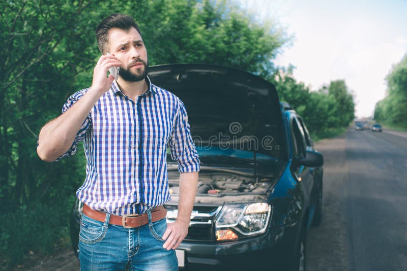Un giovane con un'automobile nera che ha ripartito sulla strada Sta richiedendo il tecnico per arrivare fotografia stock libera da diritti Un giovane con un'automobile nera che ha ripartito sulla strada Sta richiedendo il tecnico per arrivare fotografia stock libera da diritti