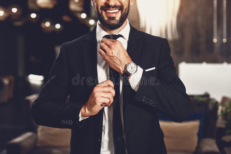 Un giovane fidato che si tocca la cravatta e sorride mentre sta da solo fotografie stock Un giovane fidato che si tocca la cravatta e sorride mentre sta da solo fotografie stock