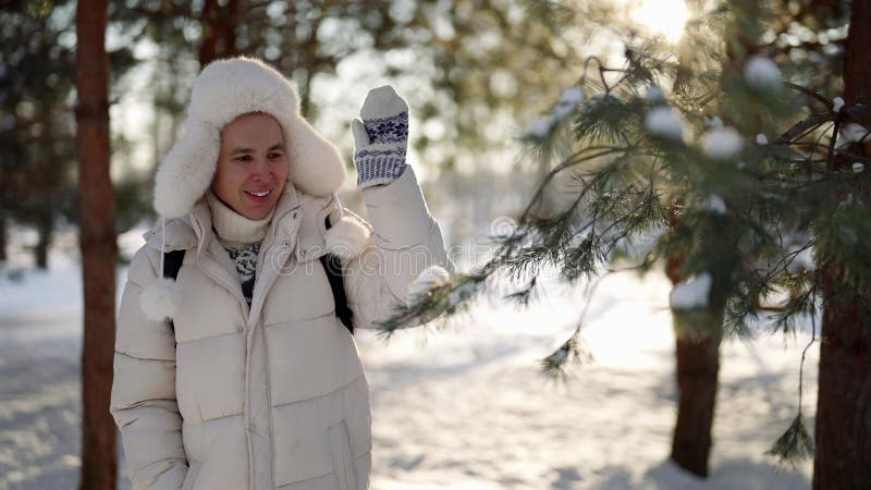 Un giovane gioioso cammina da solo nel parco e gioca con i rami di pino in inverno stock footage