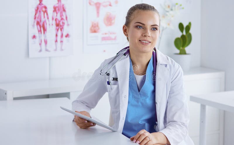 Un giovane medico femminile ad uno scrittorio nell'ufficio Il concetto della h immagini stock libere da diritti Un giovane medico femminile ad uno scrittorio nell'ufficio Il concetto della h immagini stock libere da diritti
