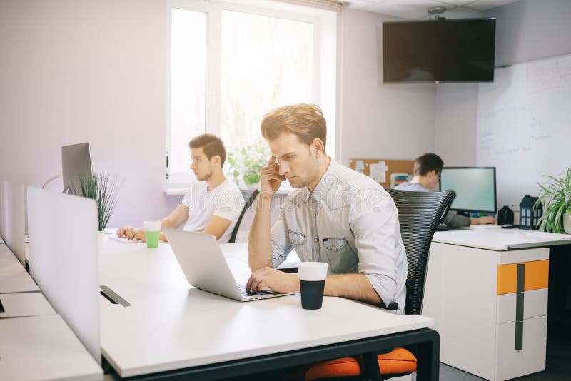 Un giovane programmatore sta esaminando il computer Il grafico sta ritenendo ai progetti futuri Il giovane tipo fotografia stock libera da diritti Un giovane programmatore sta esaminando il computer Il grafico sta ritenendo ai progetti futuri Il giovane tipo fotografia stock libera da diritti