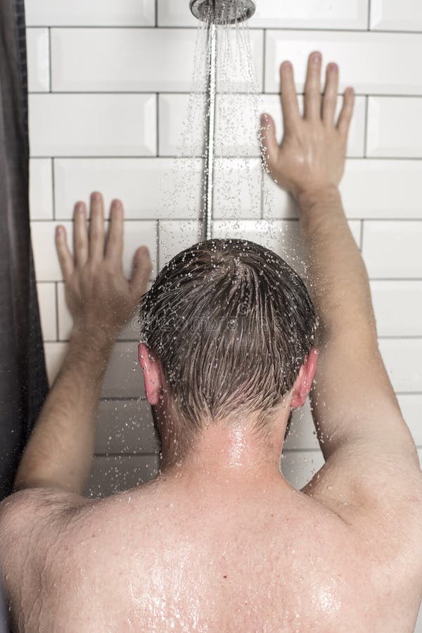 Un giovane sta nella doccia sotto acqua corrente e pende la h immagini stock libere da diritti Un giovane sta nella doccia sotto acqua corrente e pende la h immagini stock libere da diritti