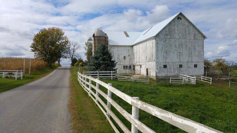 Un granero tradicional de Amish y una valla de estacas blanca en Ohio, los E.E.U.U.
