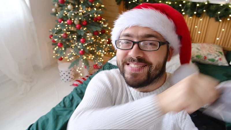 Un gros plan d'une webcam le portrait d'un type positif dans un masque médical assis près de rougeoyer décoré festif banque de vidéos