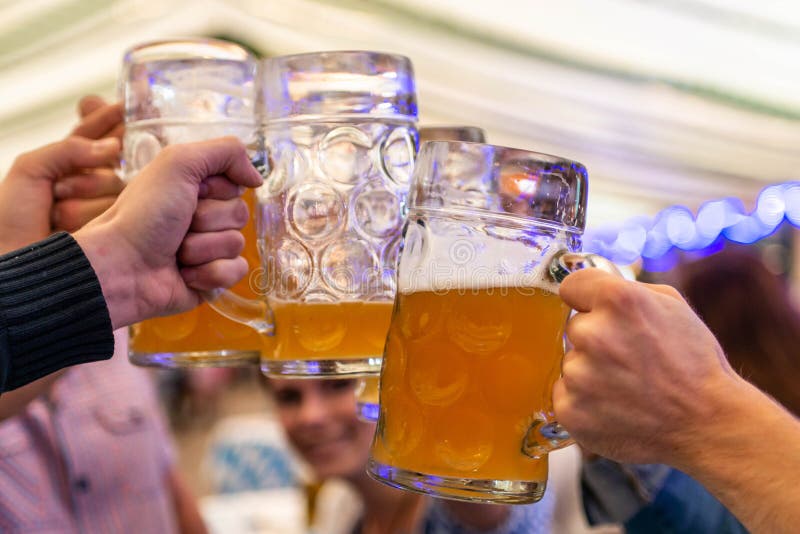 Un groupe d'amis des jeunes grillant avec des verres de bière au foyer mou d'Oktoberfest Allemagne DOF peu profond photo stock Un groupe d'amis des jeunes grillant avec des verres de bière au foyer mou d'Oktoberfest Allemagne DOF peu profond photo stock
