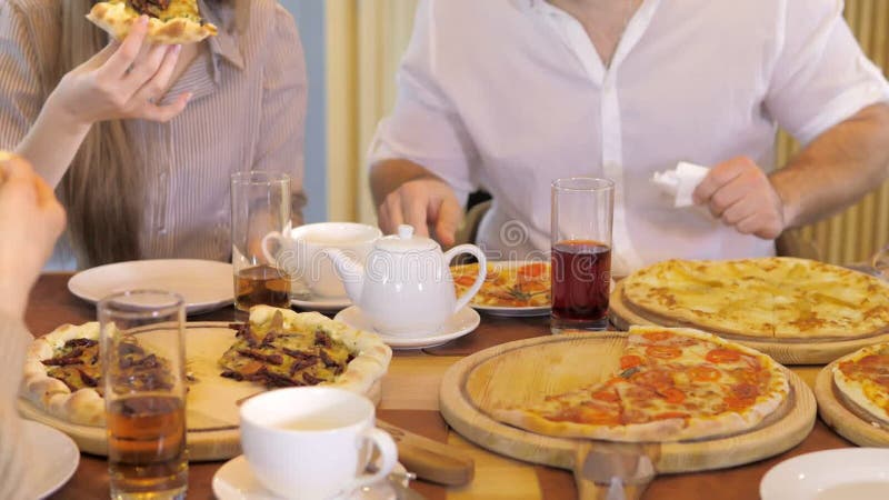 Un groupe d'amis heureux s'installe à table dans un restaurant cosy riant et s'amusant. un groupe de filles et d'hommes banque de vidéos