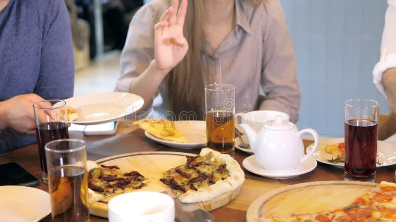 Un groupe d'amis heureux s'installe à table dans un restaurant cosy riant et s'amusant. un groupe de filles et d'hommes banque de vidéos
