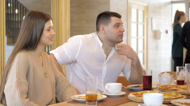 Un groupe d'amis heureux s'installe à table dans un restaurant cosy riant et s'amusant. un groupe de filles et d'hommes banque de vidéos