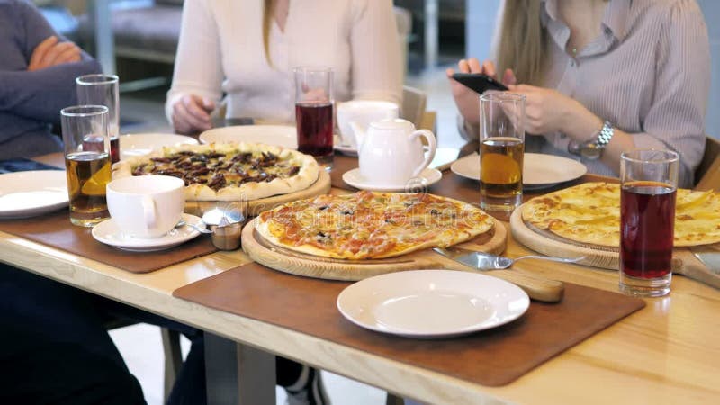 Un groupe d'amis heureux s'installe à table dans un restaurant cosy riant et s'amusant. amis ensemble dans une clips vidéos