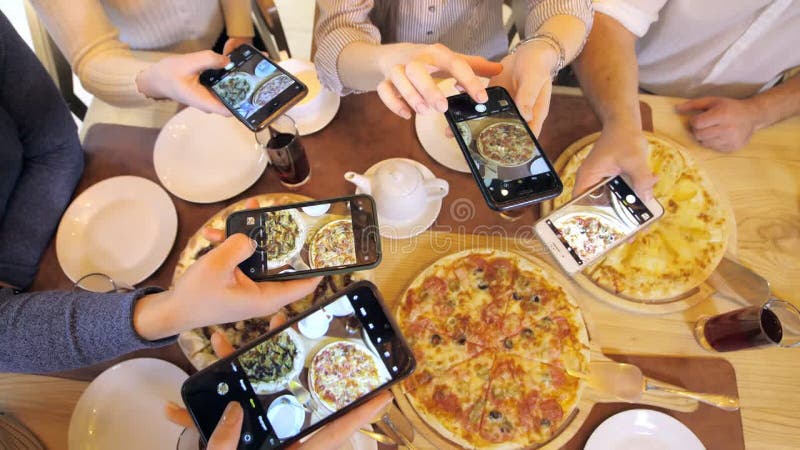 Un groupe d'amis heureux s'installe à table dans un restaurant cosy riant et s'amusant. amis ensemble dans une banque de vidéos