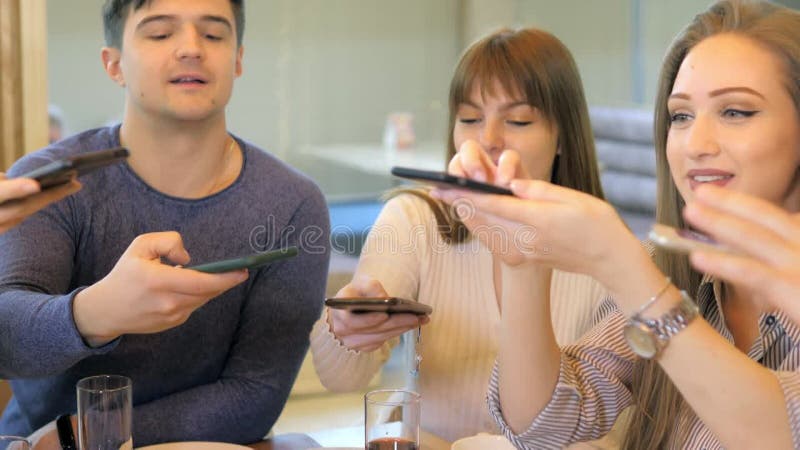 Un groupe d'amis heureux s'installe à table dans un restaurant cosy riant et s'amusant. amis ensemble dans une banque de vidéos