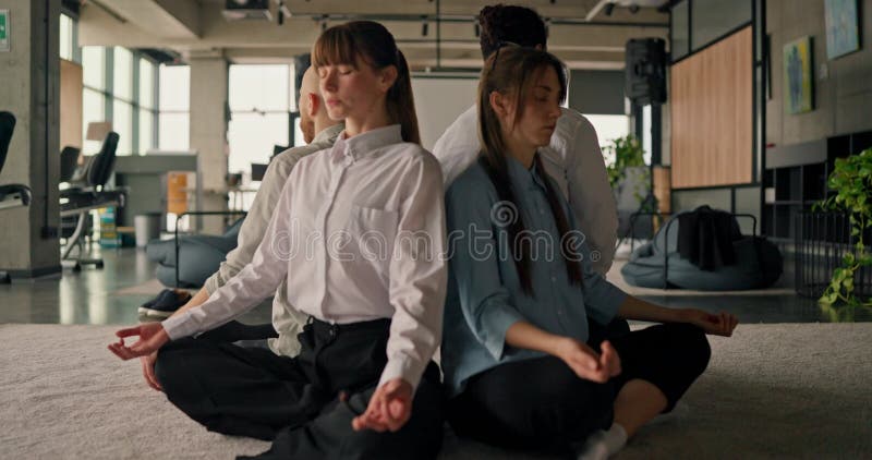 Un groupe d'employés de bureau très soudés s'installe dans la position du lotus, méditant ensemble pour améliorer le travail d'équ banque de vidéos