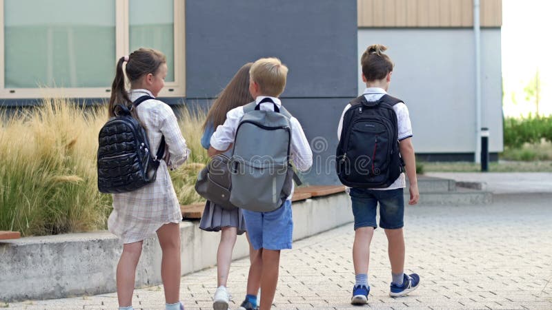 Un groupe de jeunes diplômés court joyeusement à une leçon dans la cour de l'école. banque de vidéos