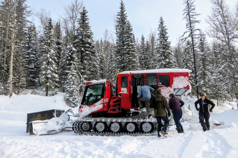 Un groupe de personnes embarquant un autoneige rouge sur le chemin à la belle loge de lac island en dehors de Fernie, la Colombie image libre de droits Un groupe de personnes embarquant un autoneige rouge sur le chemin à la belle loge de lac island en dehors de Fernie, la Colombie image libre de droits