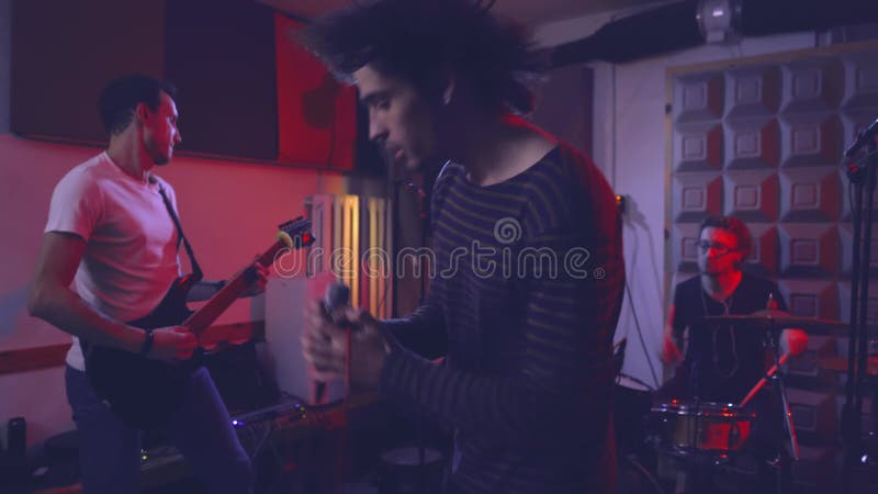 Un groupe de rock répète une nouvelle piste pour un album de musique dans la salle de répétition. banque de vidéos