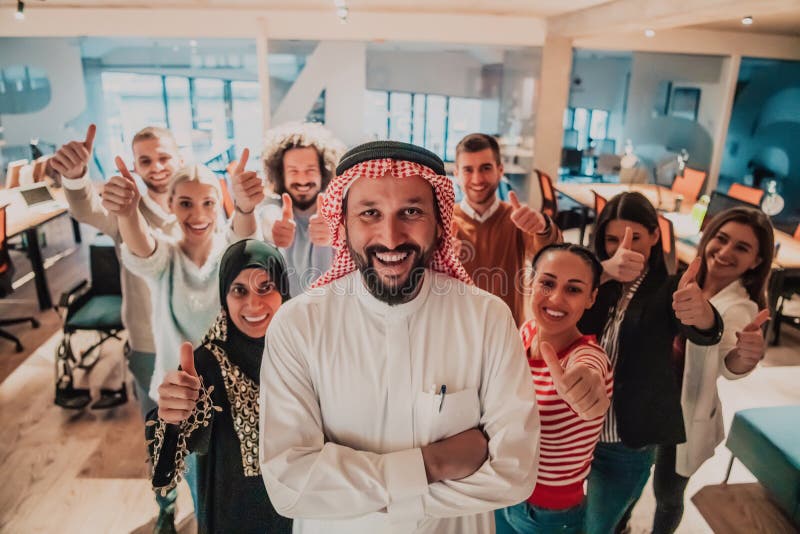 Un groupe diversifié de gens d'affaires prospères dans un bureau de verre moderne se tiennent au sommet avec leur chef arabe. photo de haute qualité.