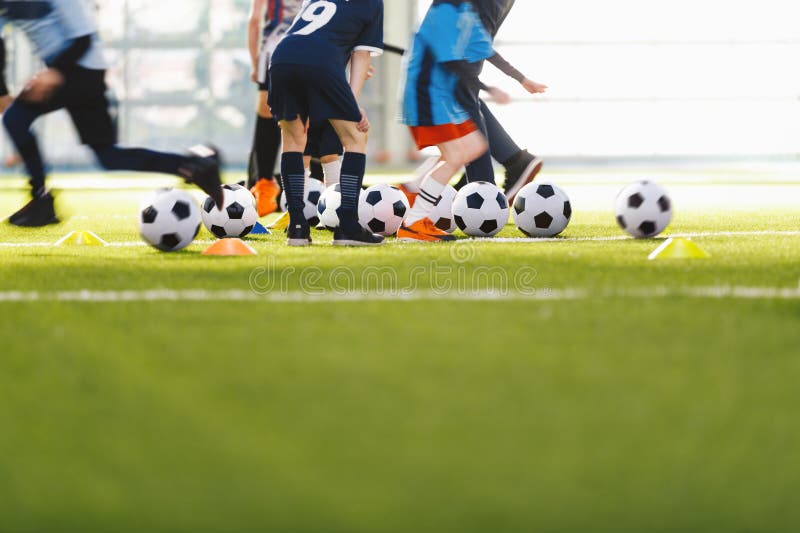 Un grupo anónimo de niños que asisten a clases de fútbol con entrenador. escolares corriendo y pateando bolas foto de archivo libre de regalías