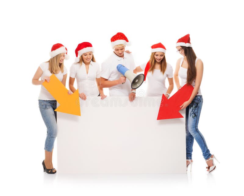 Un grupo de adolescentes en sombreros de la Navidad que señalan en un banne en blanco fotos de archivo libres de regalías Un grupo de adolescentes en sombreros de la Navidad que señalan en un banne en blanco fotos de archivo libres de regalías