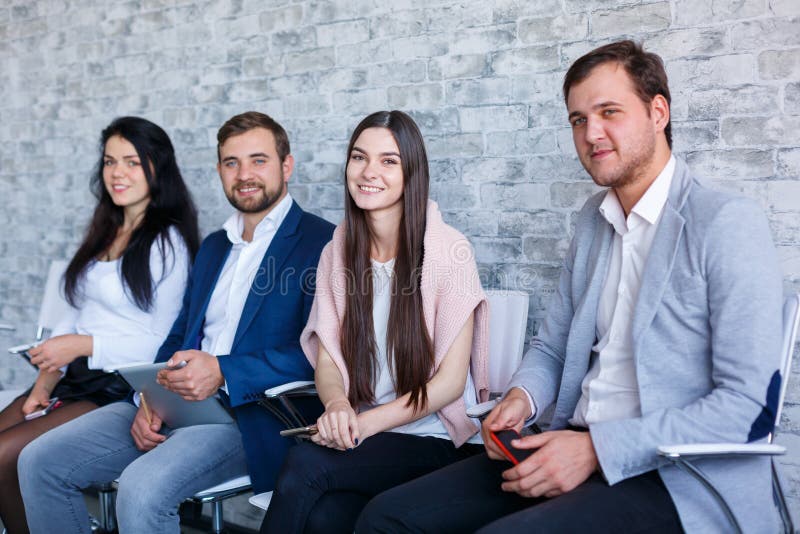 Un grupo de gente feliz, sentada y sonrisa, sosteniendo teléfonos móviles y una tableta dentro fotos de archivo Un grupo de gente feliz, sentada y sonrisa, sosteniendo teléfonos móviles y una tableta dentro fotos de archivo