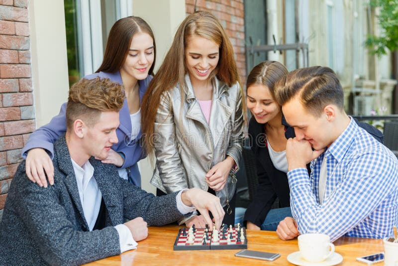 Un grupo de gente joven en un café juega a ajedrez fotos de archivo libres de regalías Un grupo de gente joven en un café juega a ajedrez fotos de archivo libres de regalías