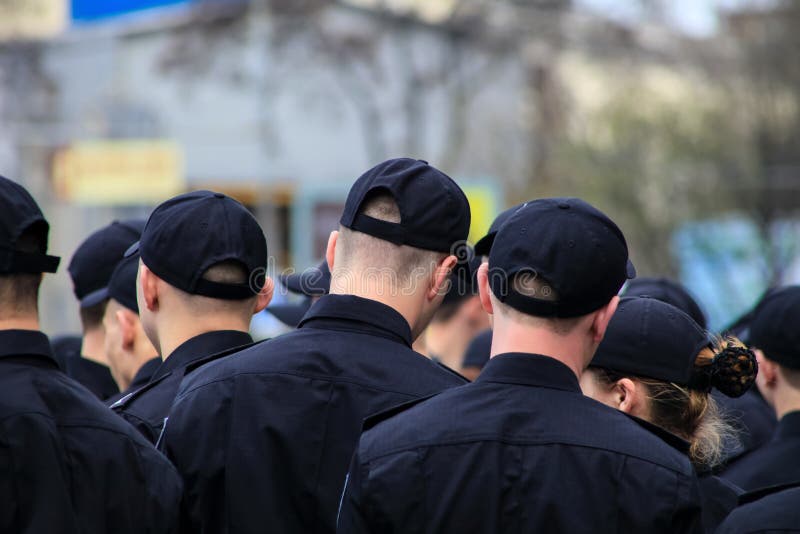 Un grupo de gente joven en uniforme negro se está colocando en una calle de la ciudad Los oficiales de policía uniformados, muc imagen de archivo libre de regalías Un grupo de gente joven en uniforme negro se está colocando en una calle de la ciudad Los oficiales de policía uniformados, muc imagen de archivo libre de regalías