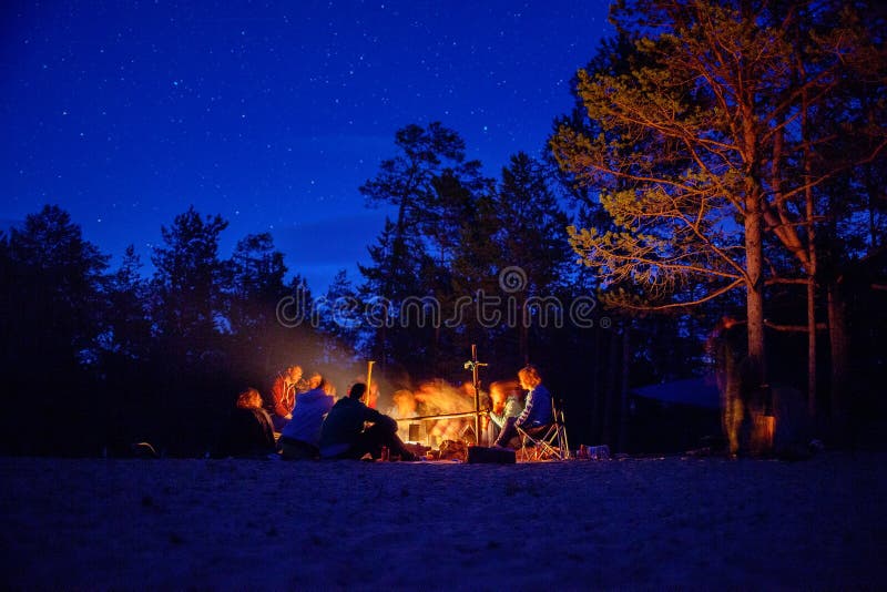 Un grupo de turistas que se sientan alrededor de la hoguera en la noche fotos de archivo Un grupo de turistas que se sientan alrededor de la hoguera en la noche fotos de archivo
