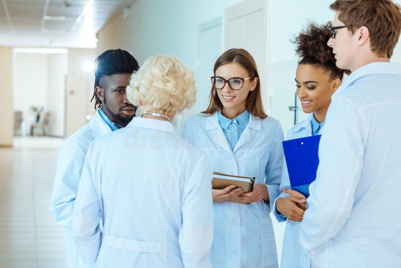 Un grupo multirracial de internos médicos en capas del laboratorio que discuten el trabajo foto de archivo libre de regalías Un grupo multirracial de internos médicos en capas del laboratorio que discuten el trabajo foto de archivo libre de regalías